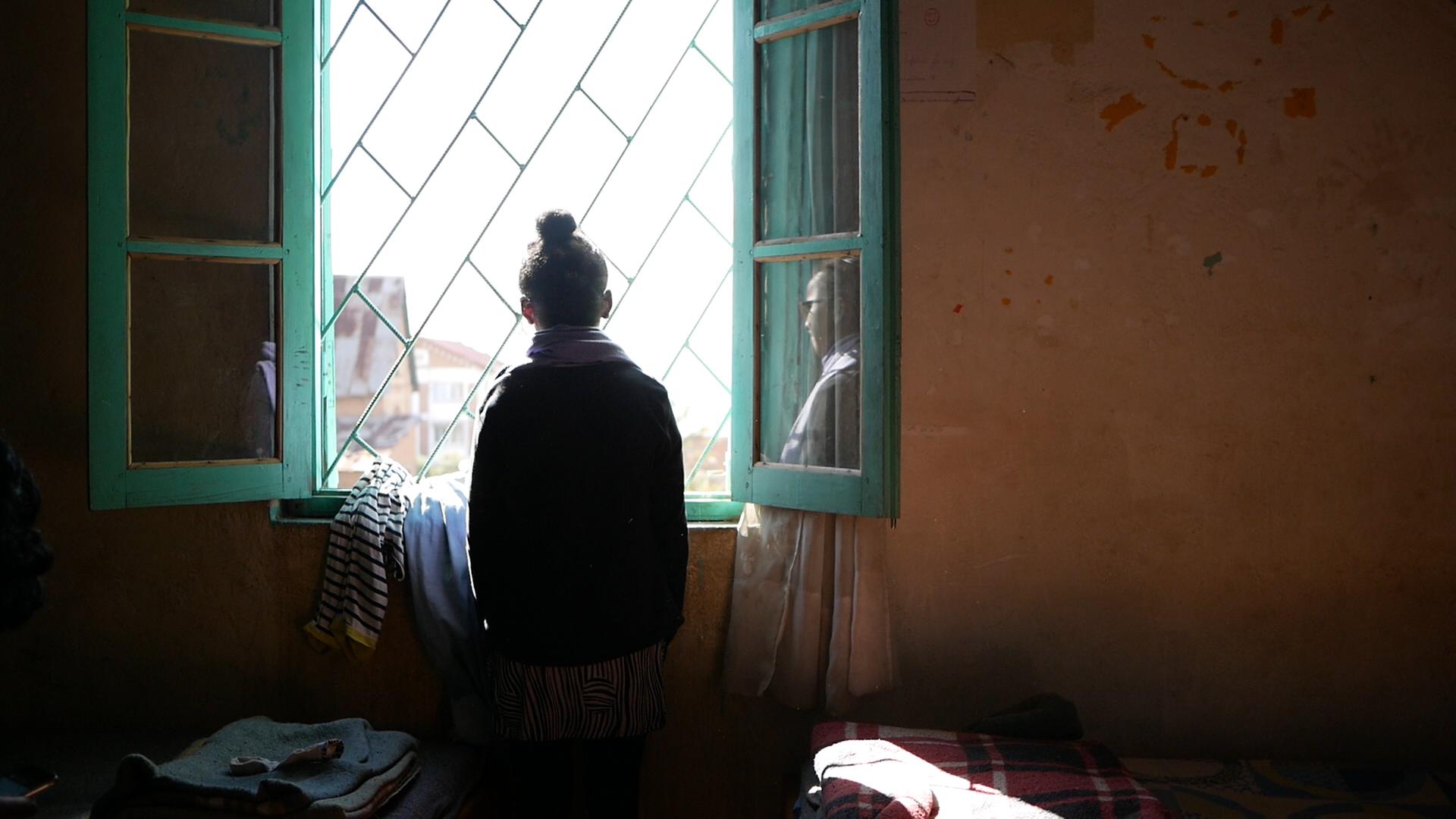 Melancholische Rückaufnahme eines jungen Mädchen, das aus einem Fenster nach draußen schaut. Melancholische Rückaufnahme eines jungen Mädchen, das aus einem Fenster nach draußen schaut.