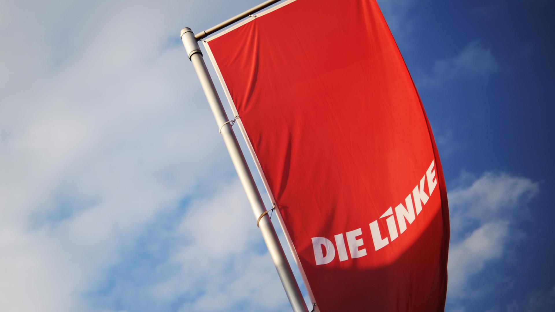 Eine Fahne der Linkspartei weht vor einem blauen Himmel.