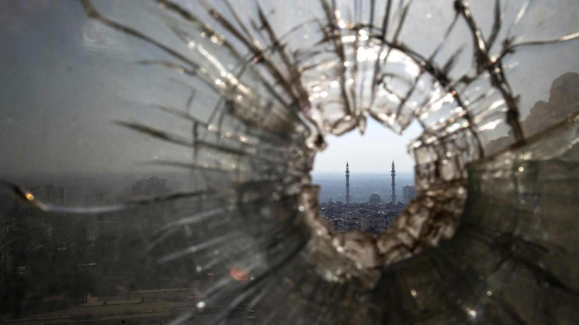 Blick durch ein zerschossenes Fenster auf eine Stadt in der arabischen Welt Blick durch ein zerschossenes Fenster auf eine Stadt in der arabischen Welt