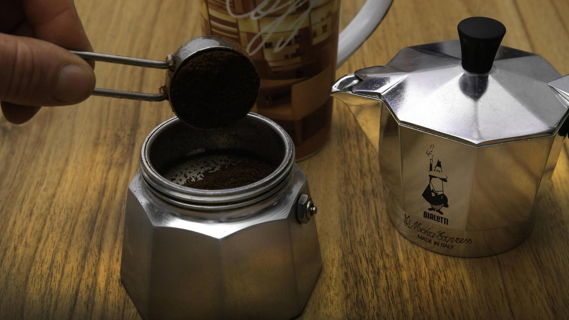 Eine Bialetti Espressokanne wird mit Kaffeepulver gefüllt. Eine Bialetti Espressokanne wird mit Kaffeepulver gefüllt.