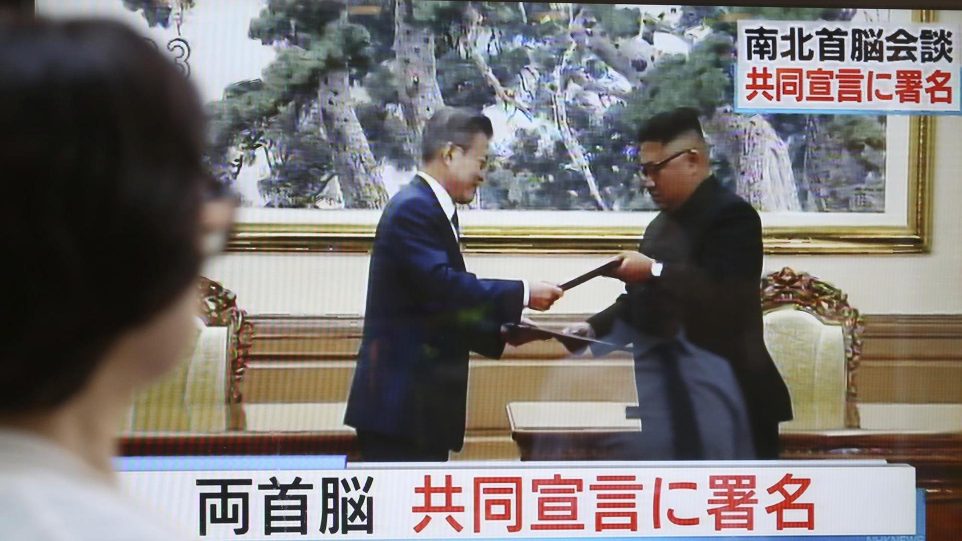 Das Bild zeigt einen Fernsehbildschirm. Auf diesem sind der nordkoreanische Machthaber Kim Jong Un und der südkoreanische Präsident Moon Jae-in zu sehen, wie sie auf dem Gipfeltreffen in Pjöngjang Dokumente austauschen. Das Bild zeigt einen Fernsehbildschirm. Auf diesem sind der nordkoreanische Machthaber Kim Jong Un und der südkoreanische Präsident Moon Jae-in zu sehen, wie sie auf dem Gipfeltreffen in Pjöngjang Dokumente austauschen.