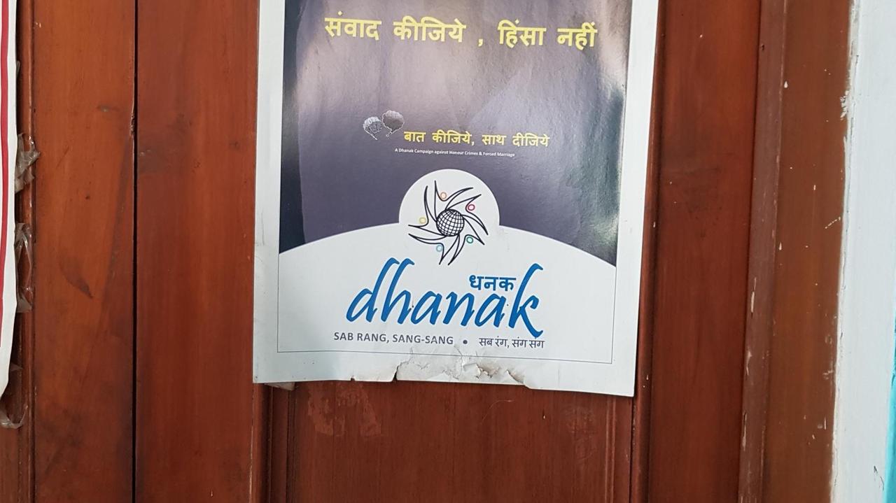 Ein Plakat, auf dem "Dhanak" steht, klebt an einer Holztür.