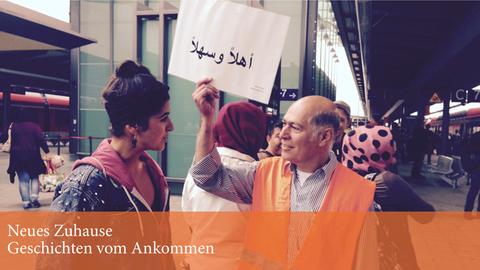 Dr. Hikmat Al-Sabty begrüßt am Rostocker Bahnhof ankommende Flüchtlinge mit einem Willkommensschild.