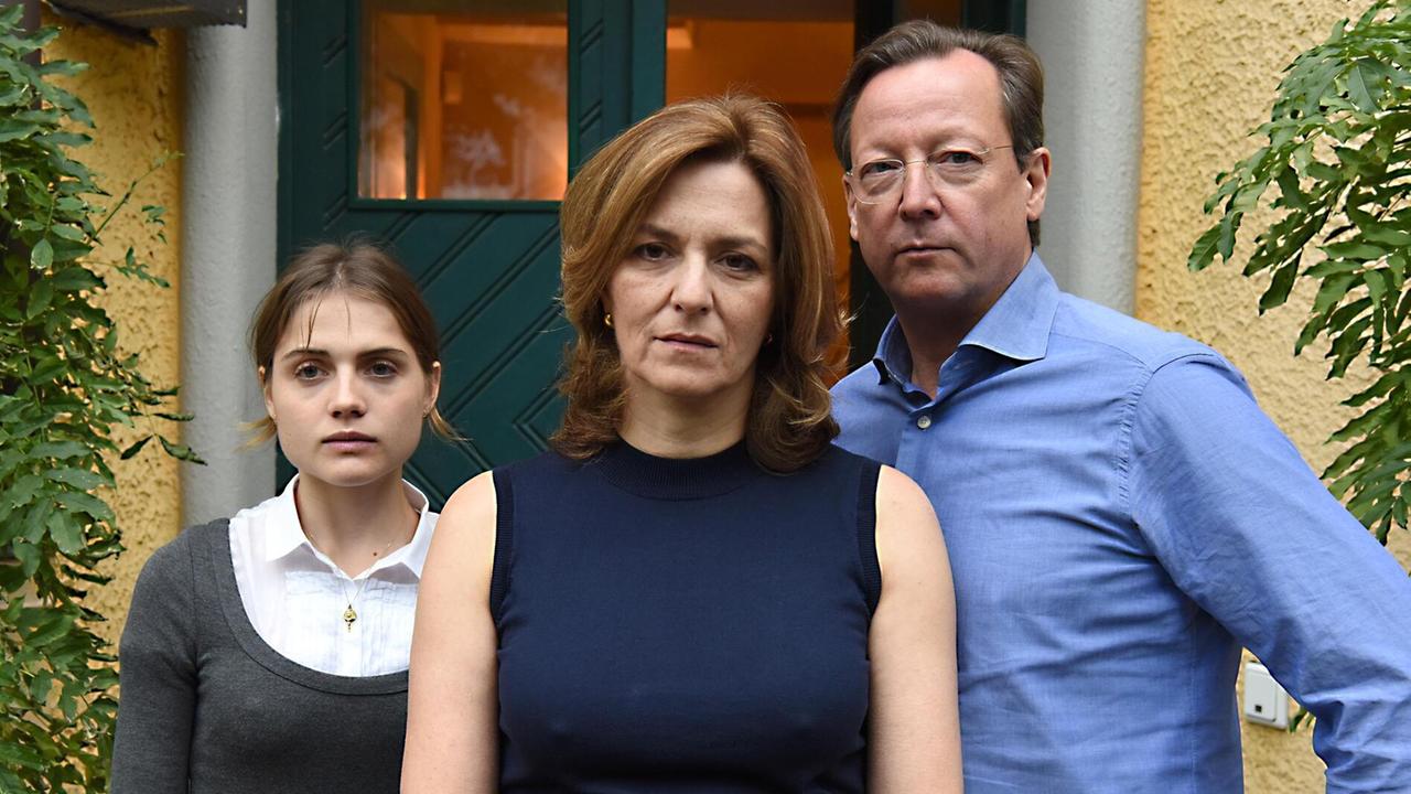 Im Still aus "Wir töten Stella" stehen Mala Emde, Martina Gedeck (mittig) und Matthias Brandt mit ernsten Blicken vor einer Haustür. Im Still aus "Wir töten Stella" stehen Mala Emde, Martina Gedeck (mittig) und Matthias Brandt mit ernsten Blicken vor einer Haustür.