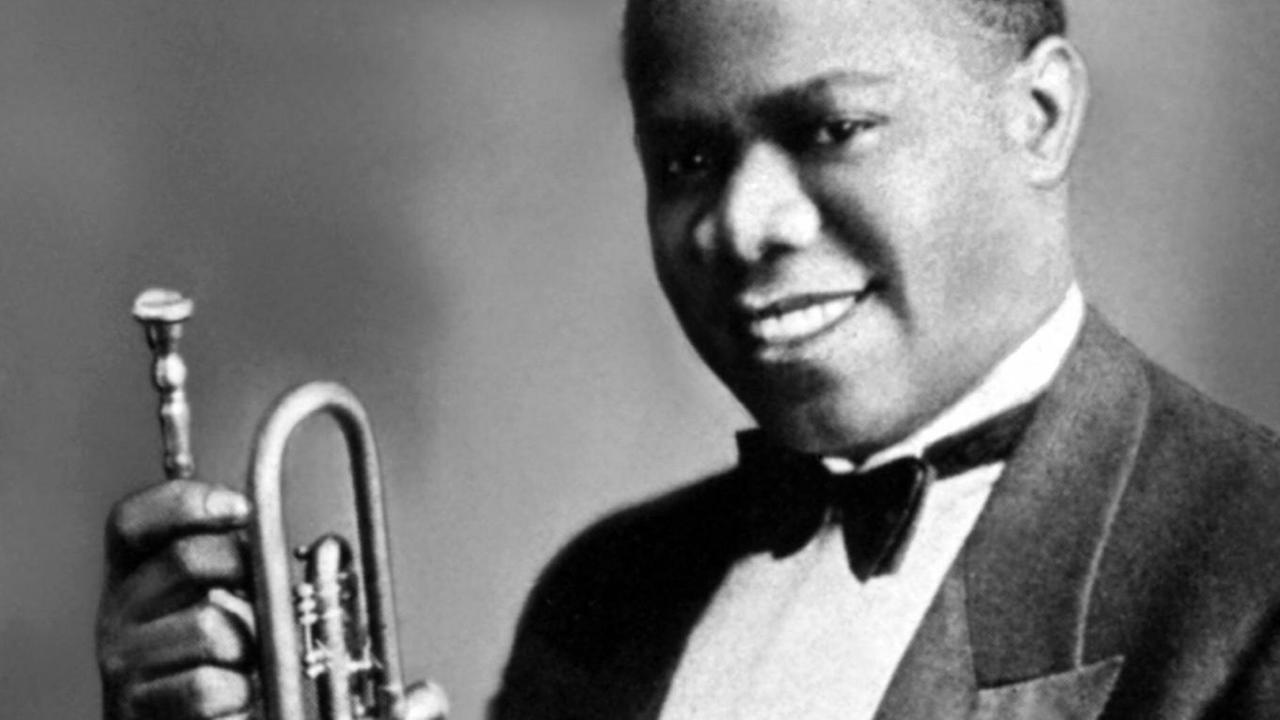 Louis Armstrong im Alter von 19 Jahren, der in Bühnenkleidung lachend sein Instrument präsentiert. Louis Armstrong im Alter von 19 Jahren, der in Bühnenkleidung lachend sein Instrument präsentiert.