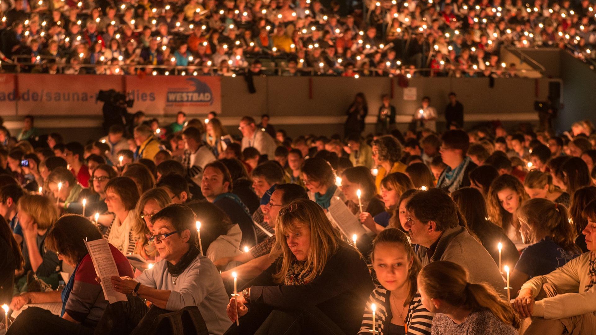 Gläubige sitzen am 30. Mai 2014 bei einem Abendgebet mit brennenden Kerzen in der Donauarena in Regensburg. Gläubige sitzen am 30. Mai 2014 bei einem Abendgebet mit brennenden Kerzen in der Donauarena in Regensburg.