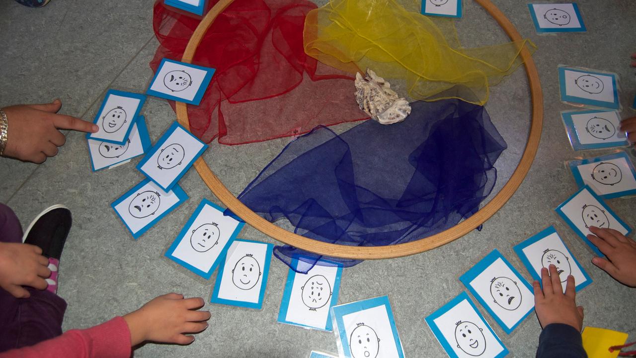 Kinder beim Resilienzkurs mit Zeichnungen lächelnder, weinender und lachender Gesichter Kinder beim Resilienzkurs mit Zeichnungen lächelnder, weinender und lachender Gesichter