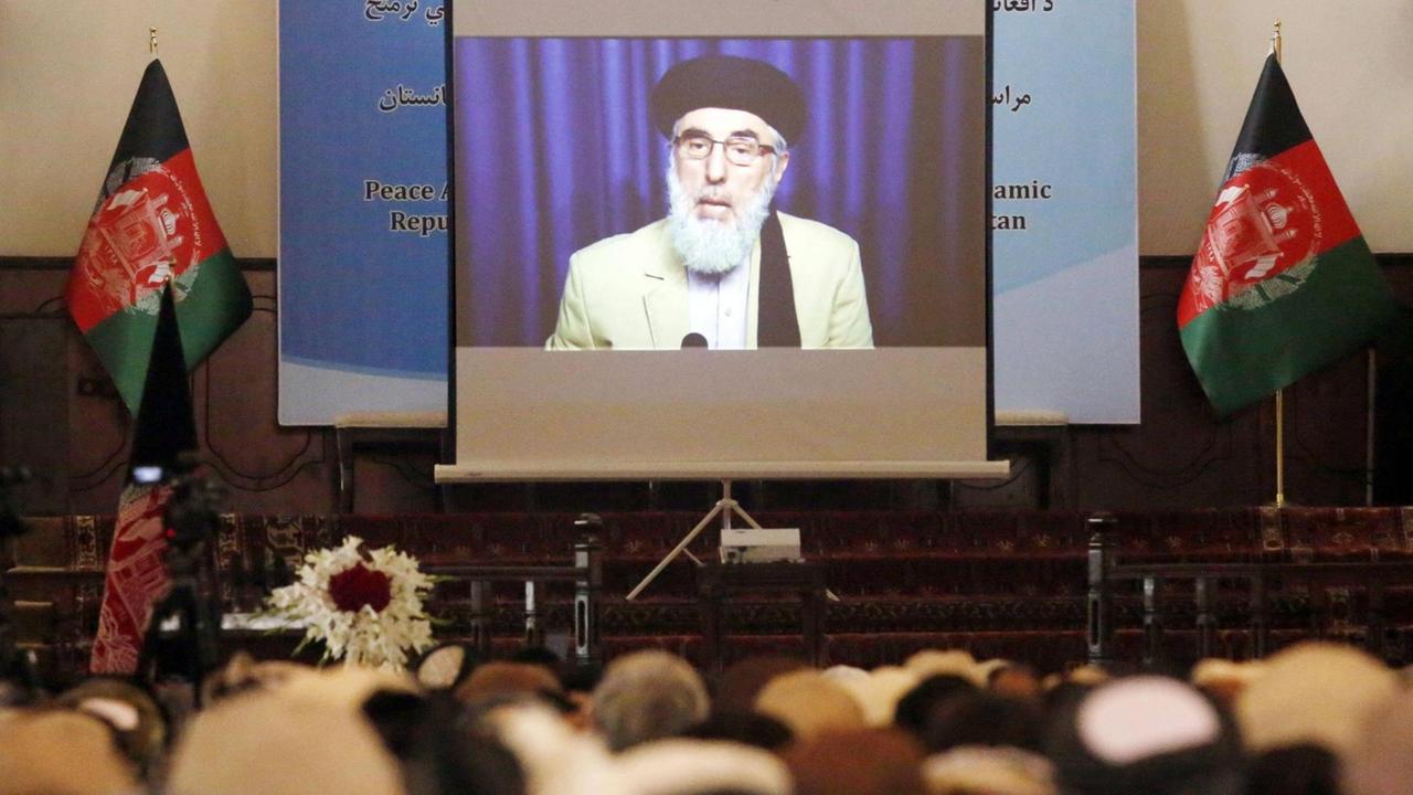 Eine Aufnahme von 2016 zeigt den Anführer der islamistischen Organisation Hezb-i-Islami Gulbuddin Hekmatyar eingeblendet auf einer Videoleinwand während der Zeremonie des Friedensvertrags im Präsidenten-Palast in Kabul.
Eine Aufnahme von 2016 zeigt den Anführer der islamistischen Organisation Hezb-i-Islami Gulbuddin Hekmatyar eingeblendet auf einer Videoleinwand während der Zeremonie des Friedensvertrags im Präsidenten-Palast in Kabul.