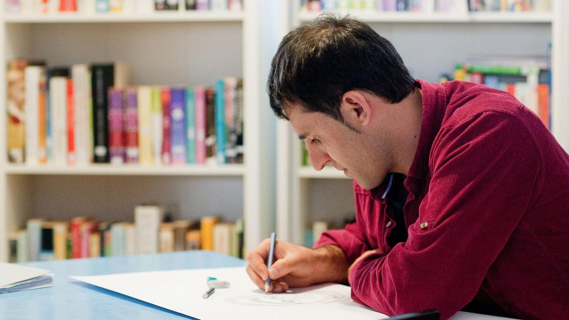Der aus Afghanistan geflohene Seyed sitzt in Berlin im Hangar eins des ehemaligen Flughafens Tempelhof in der neu eröffneten, "Asylothek" genannten Bibliothek und zeichnet ein Porträt. Neben der dortigen Unterkunft für Geflohene war ein Cafe und eine kleine Bibliothek eröffnet worden. Die Begegnungsstätte war vom Verein THFwelcome aufgebaut worden.