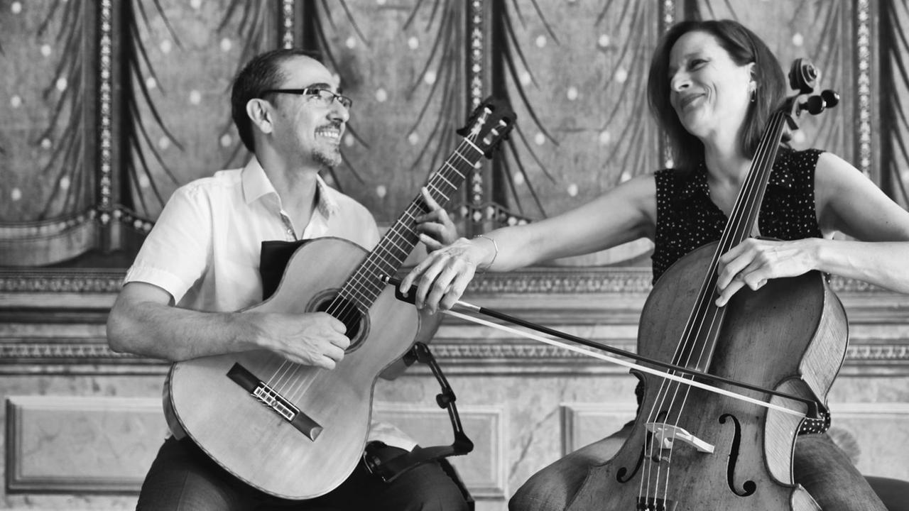 Der Gitarrist und die Cellistin spielen gemeinsam auf einer Bühne Der Gitarrist und die Cellistin spielen gemeinsam auf einer Bühne