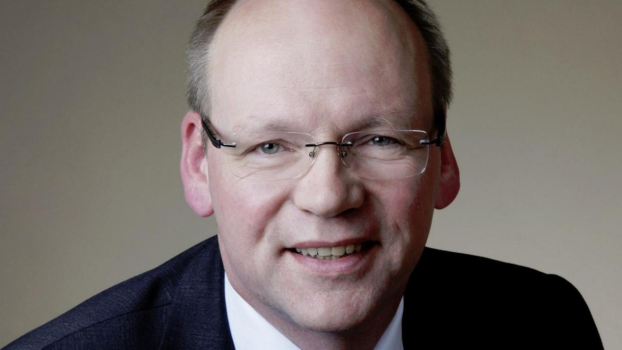 Portraitfoto: Krüsken lächelt vor einem grauen Hintergrund in die Kamera. Portraitfoto: Krüsken lächelt vor einem grauen Hintergrund in die Kamera.