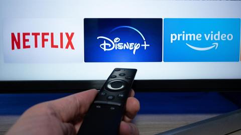 Die Logos der Streaminganbieter Netflix, Disney+ und Amazon Prime Video sind auf einem Fernseher zu sehen.