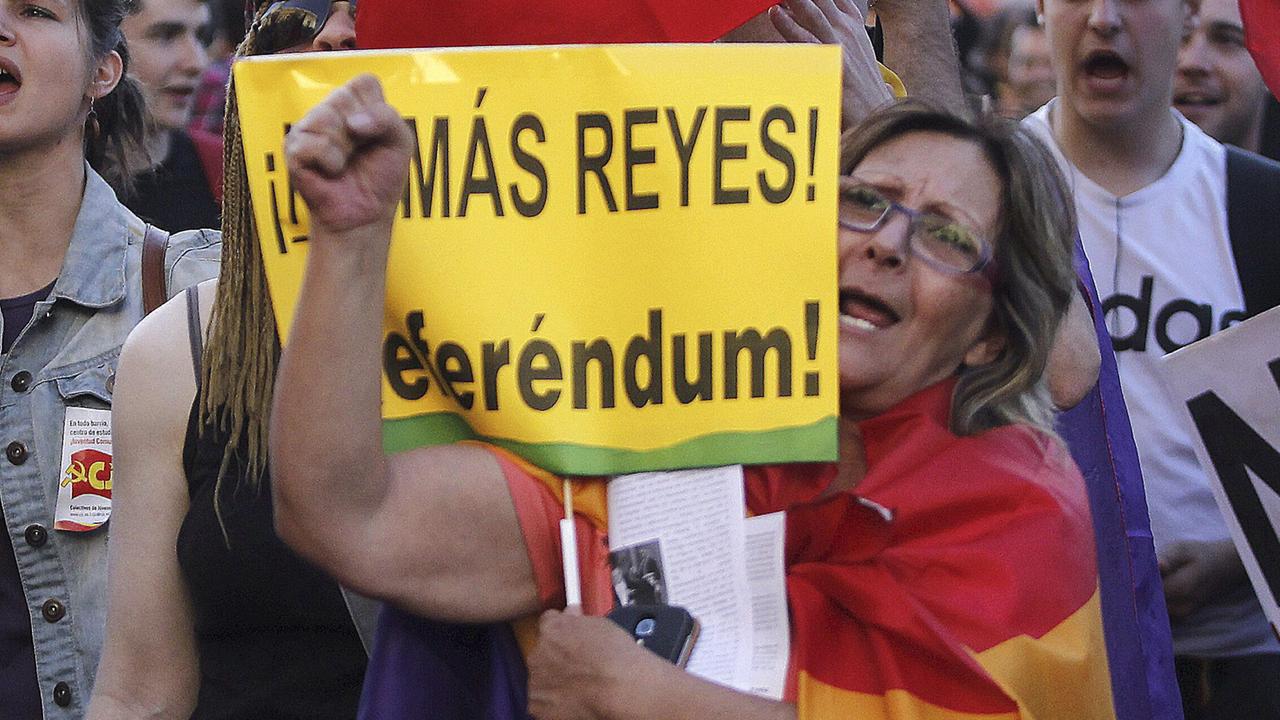 Menschen demonstrieren auf Spaniens Straßen. In der Mitte steht eine Frau mit einer Fahne um den Körper geschlungen und einem Plakat in der Hand, auf dem "Referendum" steht. Menschen demonstrieren auf Spaniens Straßen. In der Mitte steht eine Frau mit einer Fahne um den Körper geschlungen und einem Plakat in der Hand, auf dem "Referendum" steht.