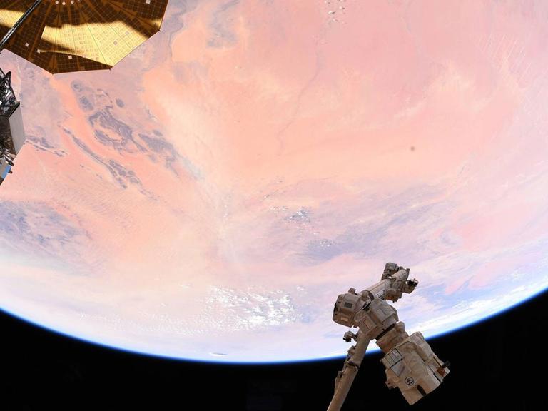 Ein Blick aus der Internationalen Raumstation ISS auf einen Teil der Erde, die von der Sonne rosa gefärbt ist