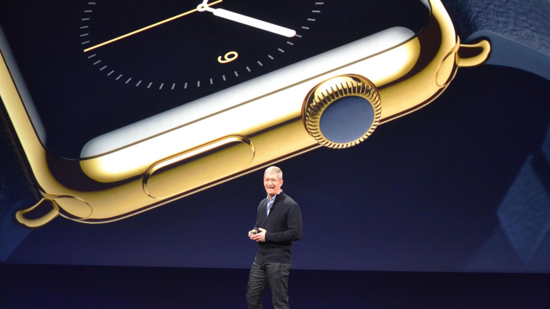 Tim Cook steht auf einer Bühne, im Hintergrund eine große Uhr auf einem Bildschirm zu sehen. Tim Cook steht auf einer Bühne, im Hintergrund eine große Uhr auf einem Bildschirm zu sehen.