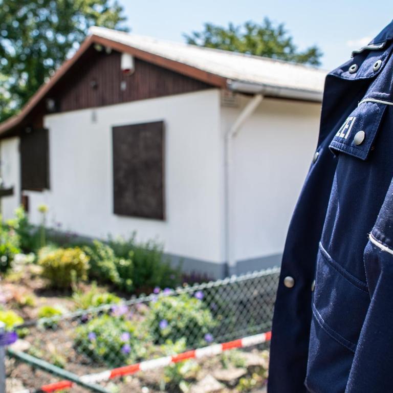 Polizeibeamter steht vor einer Gartenlaube.