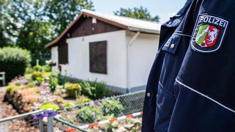 Polizeibeamter steht vor einer Gartenlaube.
