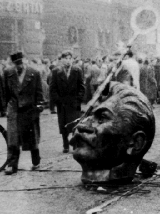 Der Kopf eines gestürzten Stalin-Denkmals auf der Straße. Am 23. Oktober 1956 fielen bei einer zunächst friedlichen Kundgebung in Budapest erste Schüsse. Arbeiter, Studenten und Jugendliche bewaffneten sich und nahmen den Kampf gegen die einrückenden sowjetischen Truppen auf.