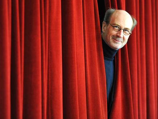 Der Geschäftsführende Direktor des Deutschen Bühnenvereins, Rolf Bolwin, schaut im Deutschen Schauspielhaus in Hamburg zwischen einem Theatervorhang hervor.