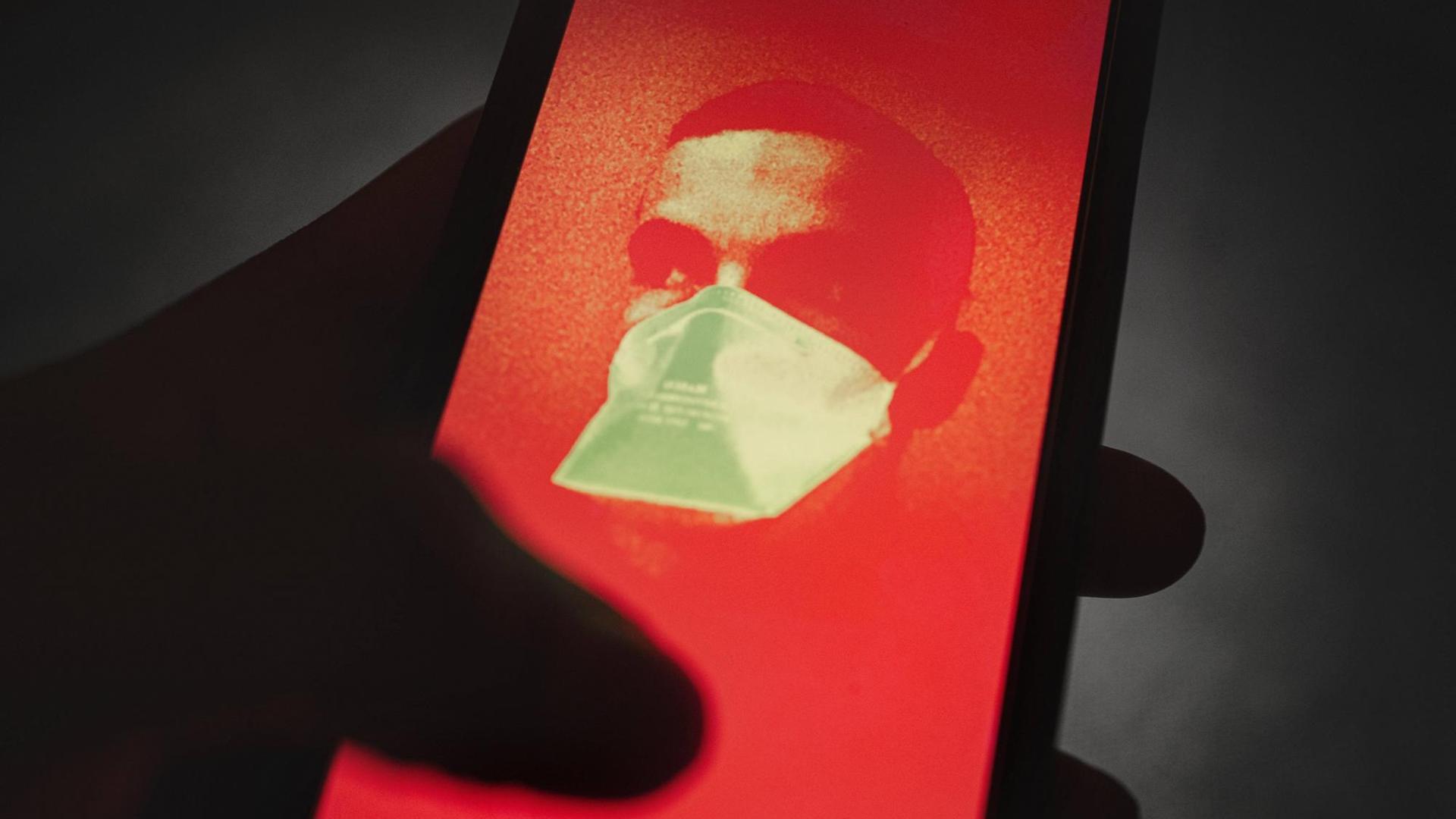 Illustration: Mit einer Wärmebildkamera aufgenommenes Bild einer Person auf einem Smartphone-Display Illustration: Mit einer Wärmebildkamera aufgenommenes Bild einer Person auf einem Smartphone-Display