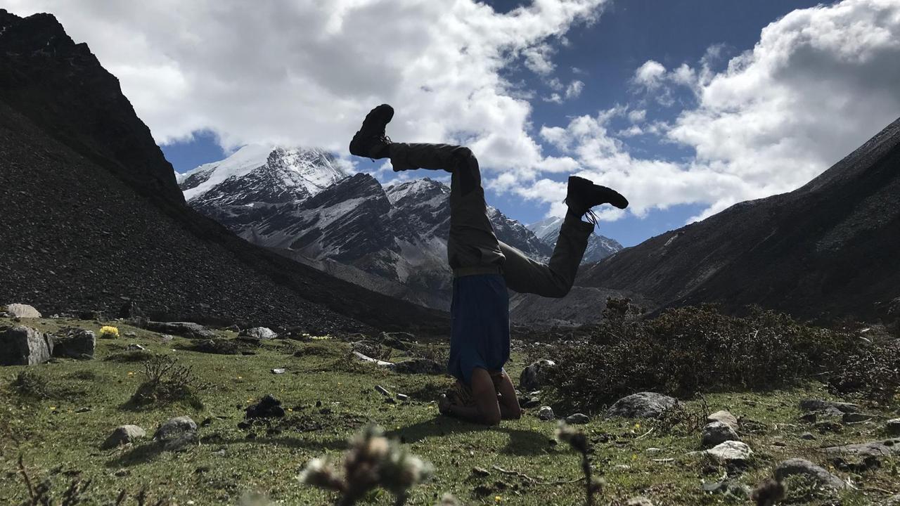 Ein Mann macht in einer Berglandschaft einen Handstand. Ein Mann macht in einer Berglandschaft einen Handstand.