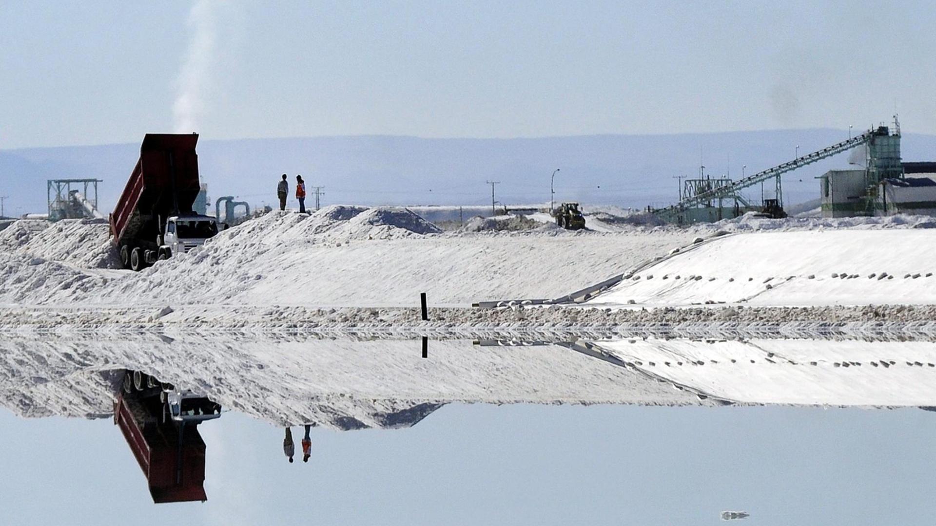 Menschen und Fahrzeuge spiegeln sich in Salzbecken des Lithiums-Abbaus in Atacama, nahe Calama City, in Chile.