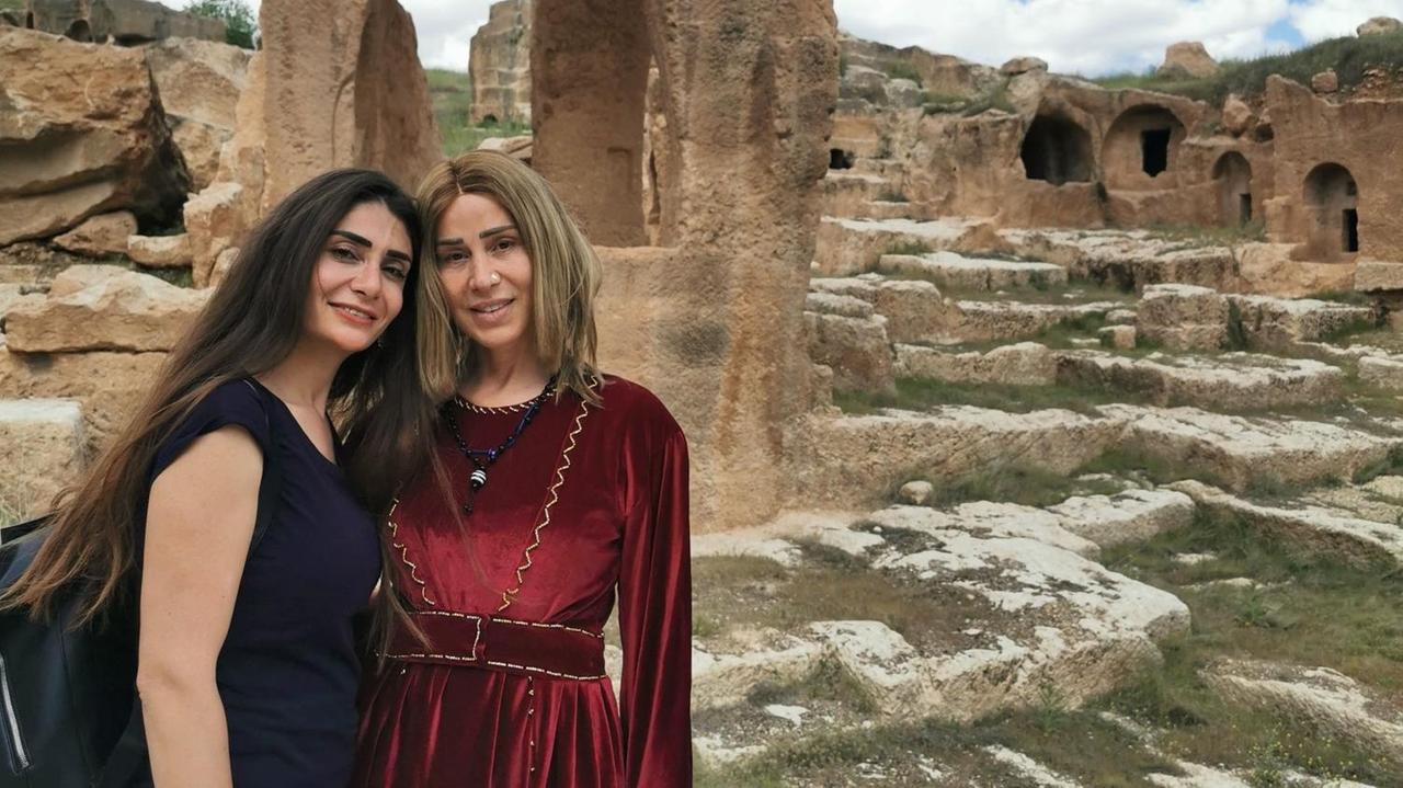 Zwei aneinandergelehnte Frauen stehen vor eine alten Stadt aus Stein auf einer Grünfläche. Zwei aneinandergelehnte Frauen stehen vor eine alten Stadt aus Stein auf einer Grünfläche.
