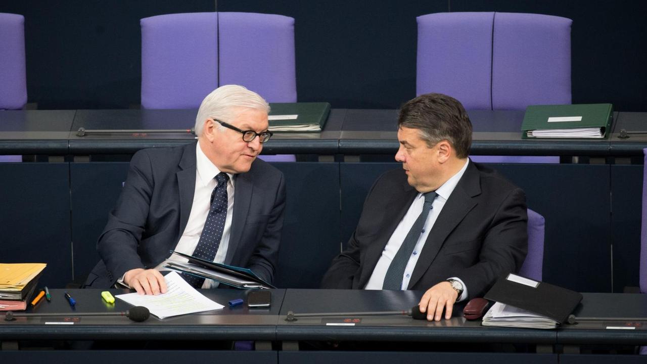 Steinmeier und Gabriel sitzen alleine in schwarzen Anzügen auf der Regierungsbank und reden. Die Sitzreihe hinter ihnen ist leer. Steinmeier und Gabriel sitzen alleine in schwarzen Anzügen auf der Regierungsbank und reden. Die Sitzreihe hinter ihnen ist leer.