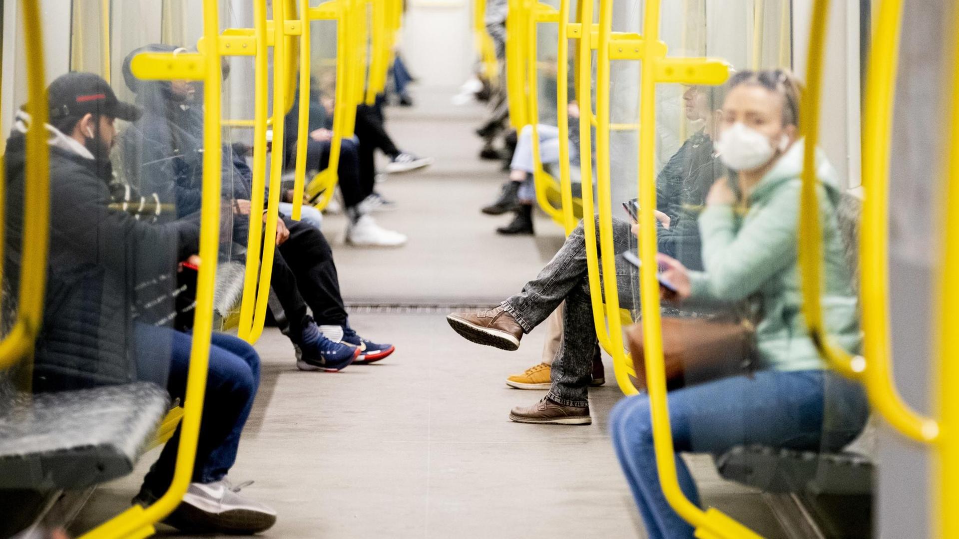 Fahrgäste sitzen in einer U-Bahn, eine Frau trägt einen Mundschutz. Fahrgäste sitzen in einer U-Bahn, eine Frau trägt einen Mundschutz.
