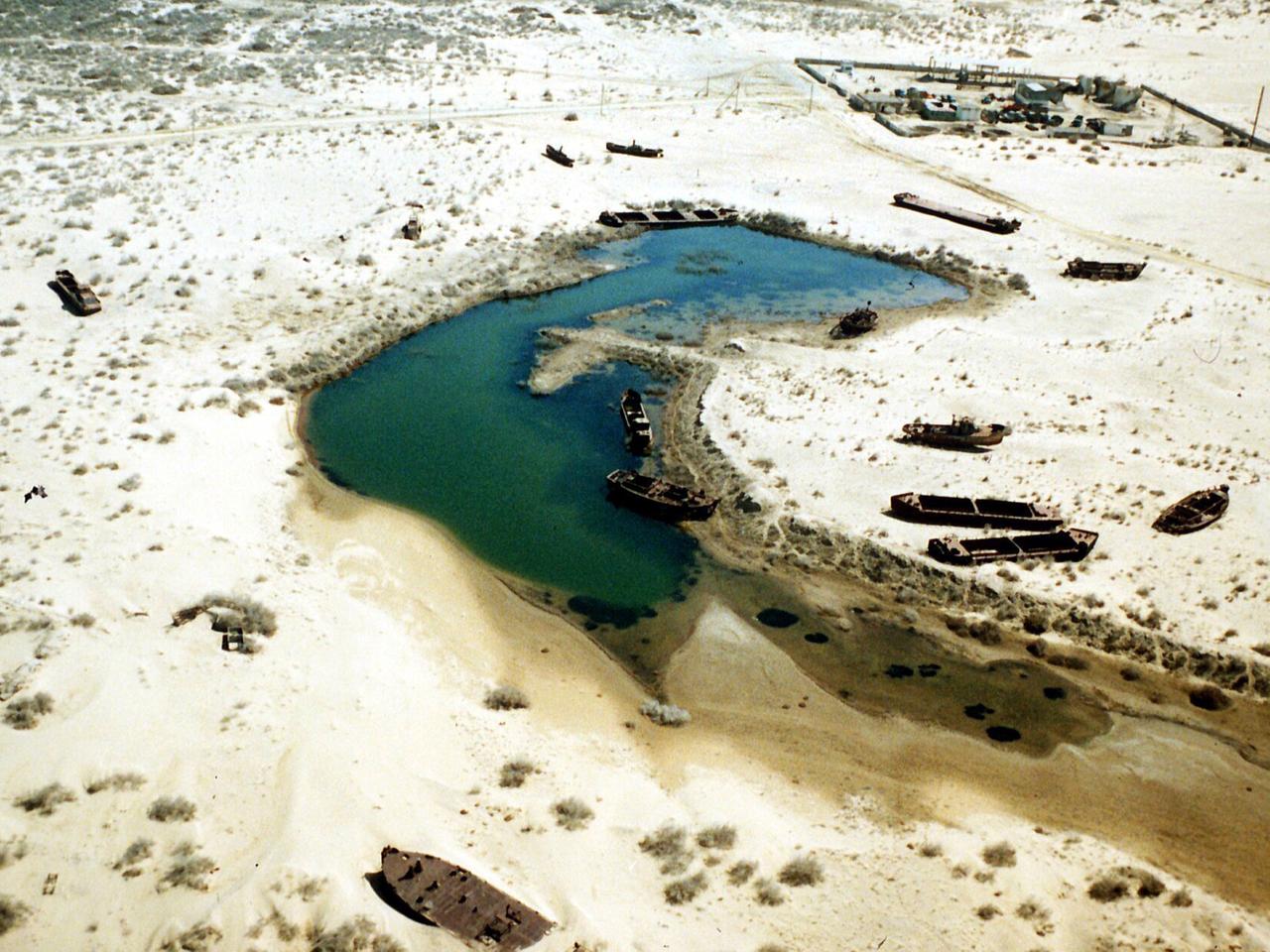 Boote auf dem Trockenen in einem Gebiet, das früher vom Wasser des Aralsees bedeckt war, aufgenommen in Usbekistan 1996. Der Aralsee gehört zu den früheren Sowjetrepubliken Kasachstan (im Norden) und Usbekistan (im Süden des Sees). Er war usprünglich mit 65000 Quadratkilometern fast so groß wie Bayern, hat aber seit 1969 mehr als 40 Prozent seiner Fläche verloren. Frühere Hafenstädte liegen heute in Salzwüsten, die bis zu 50 Kilometer vom Ufer entfernt sind. Ursache ist eine zu große Wasserentnahme aus den beiden Zuflüssen Amu Darja und Syr Darja zur Bewässerung der Baumwollplantagen in beiden Ländern. Boote auf dem Trockenen in einem Gebiet, das früher vom Wasser des Aralsees bedeckt war, aufgenommen in Usbekistan 1996. Der Aralsee gehört zu den früheren Sowjetrepubliken Kasachstan (im Norden) und Usbekistan (im Süden des Sees). Er war usprünglich mit 65000 Quadratkilometern fast so groß wie Bayern, hat aber seit 1969 mehr als 40 Prozent seiner Fläche verloren. Frühere Hafenstädte liegen heute in Salzwüsten, die bis zu 50 Kilometer vom Ufer entfernt sind. Ursache ist eine zu große Wasserentnahme aus den beiden Zuflüssen Amu Darja und Syr Darja zur Bewässerung der Baumwollplantagen in beiden Ländern.