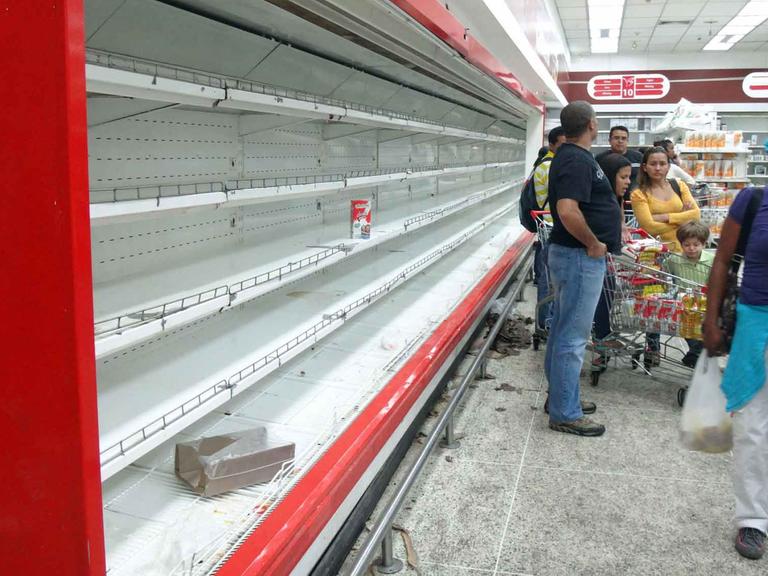 Kunden stehen im Supermarkt in Caracas, Venezuela, vor leeren Regalen.