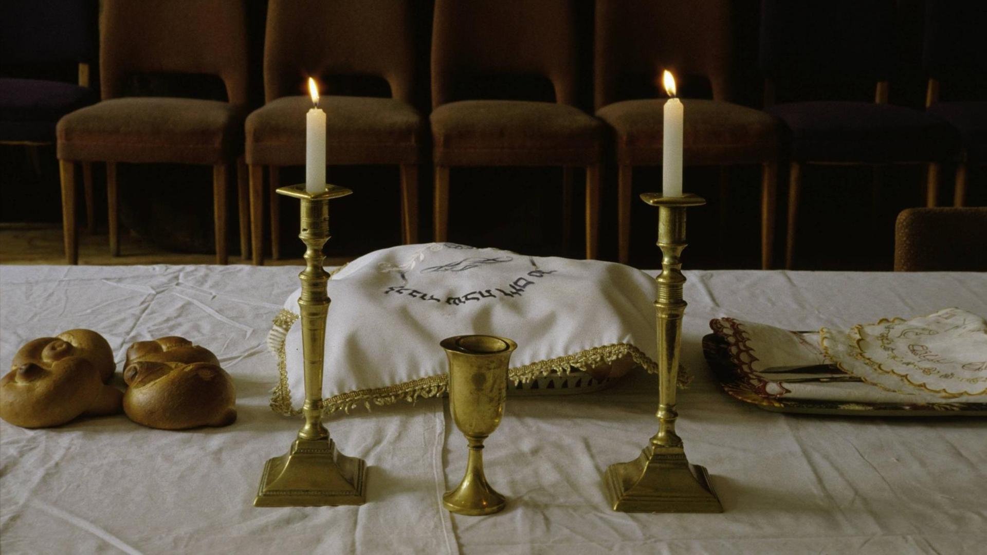 Gedeckter Tisch am Freitagabend (Beginn des Sabbats) mit angezündeten Kerzen und zwei Laiben Brot (Challa). Gedeckter Tisch am Freitagabend (Beginn des Sabbats) mit angezündeten Kerzen und zwei Laiben Brot (Challa).