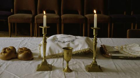 Gedeckter Tisch am Freitagabend (Beginn des Sabbats) mit angezündeten Kerzen und zwei Laiben Brot (Challa).