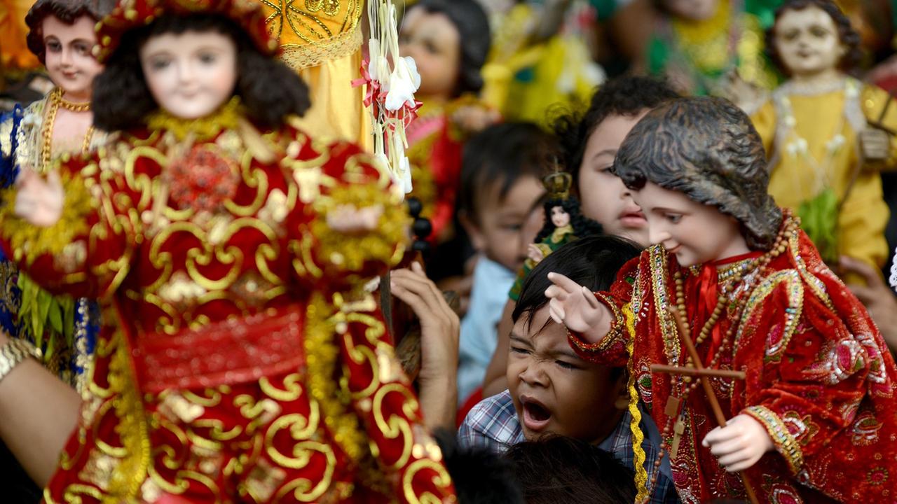 Philippinische Katholiken halten Puppen von Jesus als Kind in die Höhe. Philippinische Katholiken halten Puppen von Jesus als Kind in die Höhe.