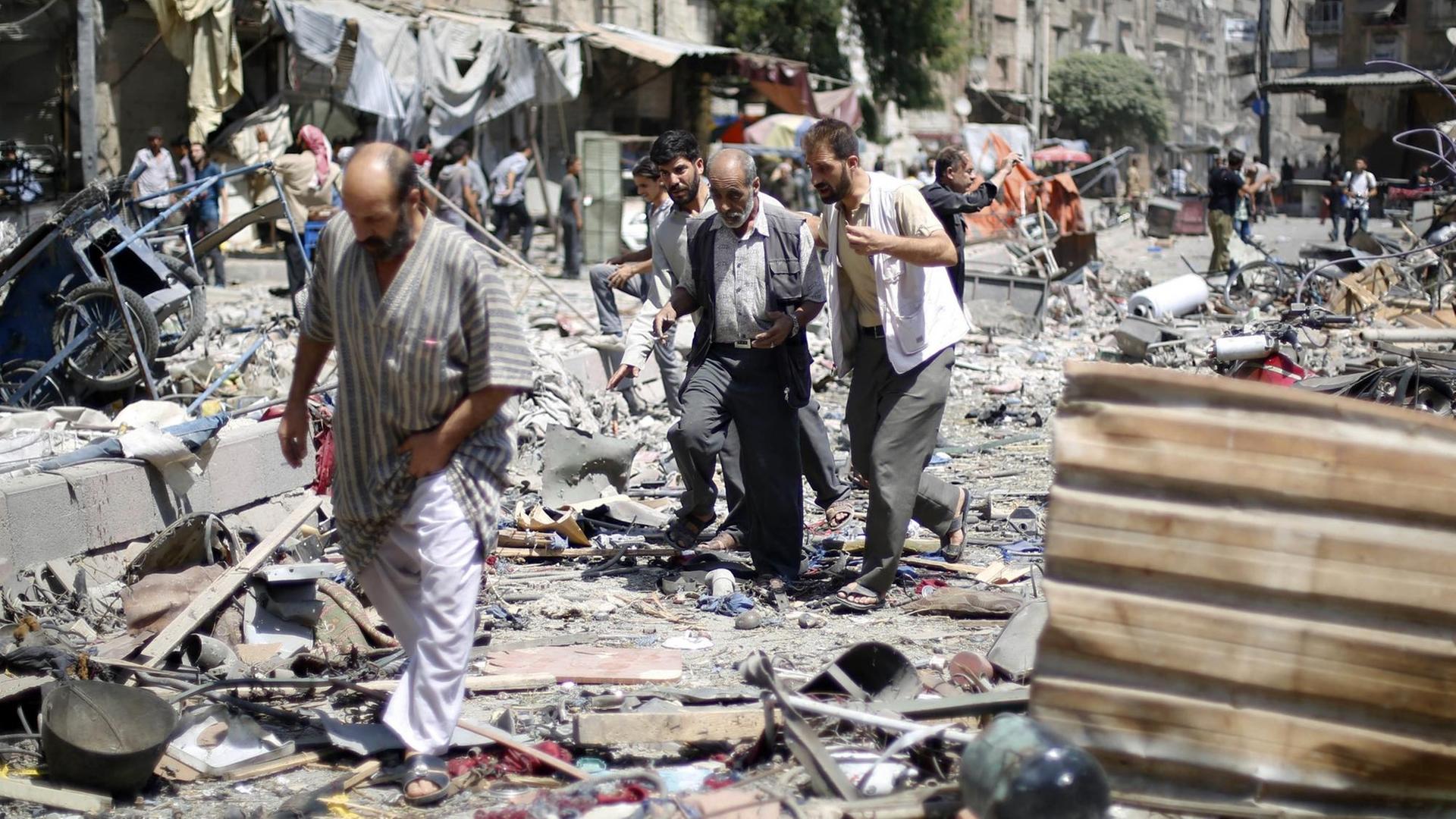 Drei Männer laufen über Schutt auf dem Marktplatz in Duma, Syrien Drei Männer laufen über Schutt auf dem Marktplatz in Duma, Syrien