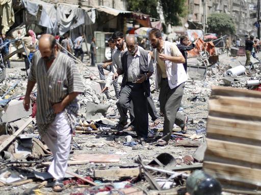 Drei Männer laufen über Schutt auf dem Marktplatz in Duma, Syrien