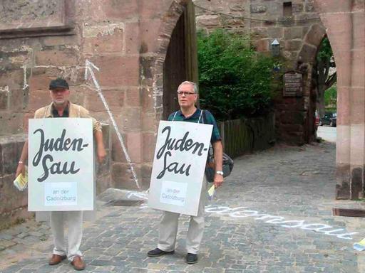 Die Künstler Wolfram Kastner (links) und Günter Wangerin demonstrieren gegen ein umstrittenes Relief an der Cadolzburg im mittelfränkischen Landkreis Fürth.