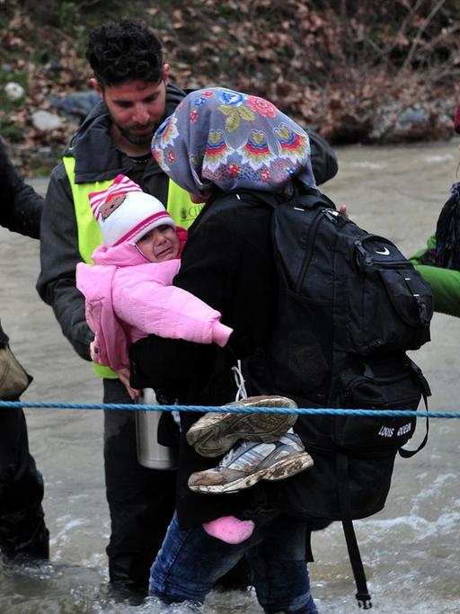 Flüchtlinge überqueren einen Fluss an der Grenze zwischen Griechenland und Mazedonien
