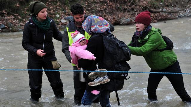 Flüchtlinge überqueren einen Fluss an der Grenze zwischen Griechenland und Mazedonien