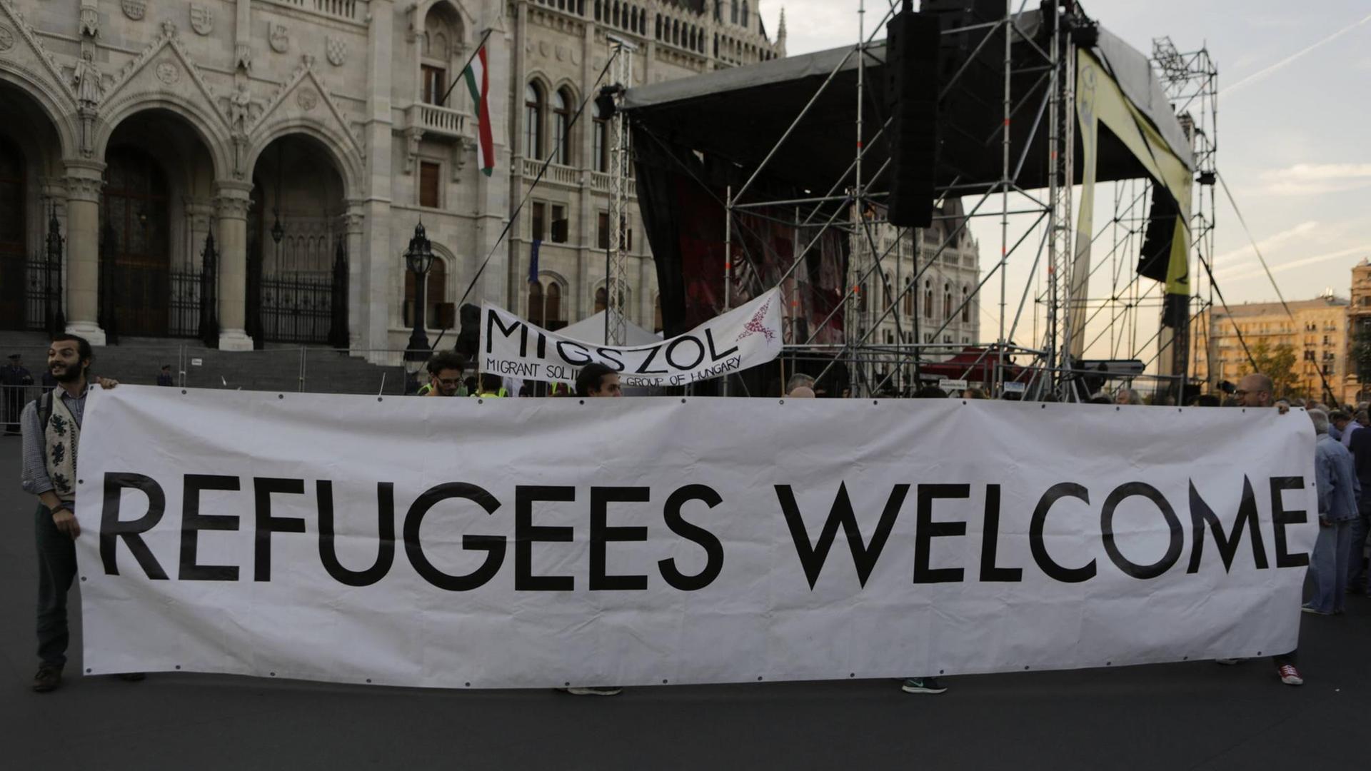 Eine Gruppe von Aktivisten protestiert gegen die Politik ihrer ungarischen Regierung und hält ein Schild, auf dem steht: Refugees welcome, Flüchtlinge willkommen. Eine Gruppe von Aktivisten protestiert gegen die Politik ihrer ungarischen Regierung und hält ein Schild, auf dem steht: Refugees welcome, Flüchtlinge willkommen.