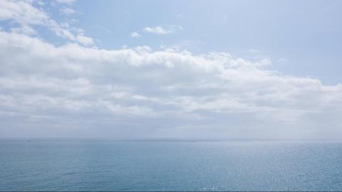 Meer mit blauem Himmel und weißen Wolken am Horizont.
