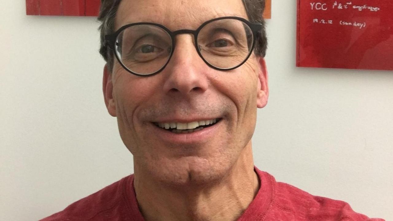 Professor Peter Kaiser lächelt freundlich in die Kamera, im Hintergrund: ein rotes abstraktes Gemälde. Professor Peter Kaiser lächelt freundlich in die Kamera, im Hintergrund: ein rotes abstraktes Gemälde.
