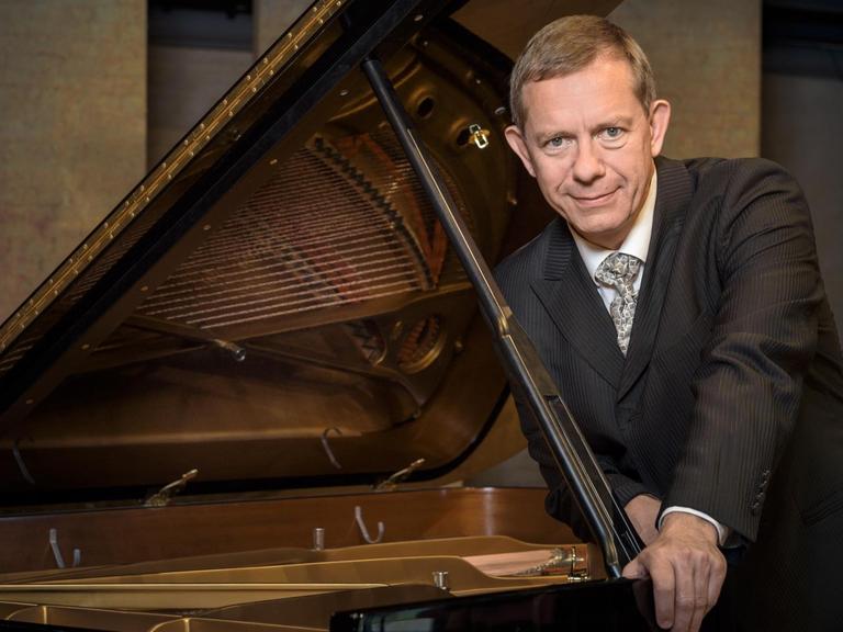 Der Pianist lehnt sich vorsichtig an den geöffneten Flügel.