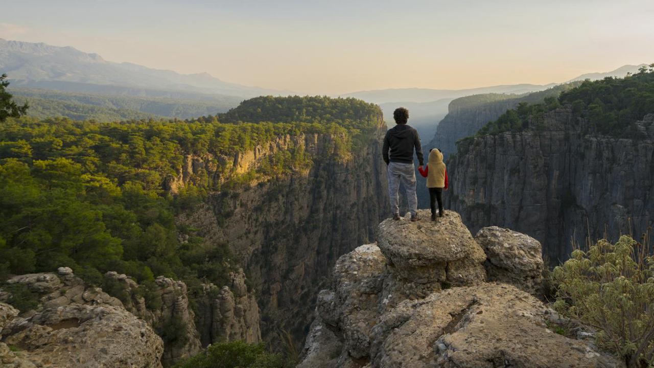 Ein Mann steht mit seinem Kind auf einem Felsen an der Tazi Schlucht in Antalya und schaut in die Ferne Ein Mann steht mit seinem Kind auf einem Felsen an der Tazi Schlucht in Antalya und schaut in die Ferne