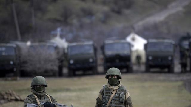 Bewaffnete Männer, die für russische Soldaten gehalten werden, stehen vor einem ukrainischen Militärstützpunkt in Perewalne
