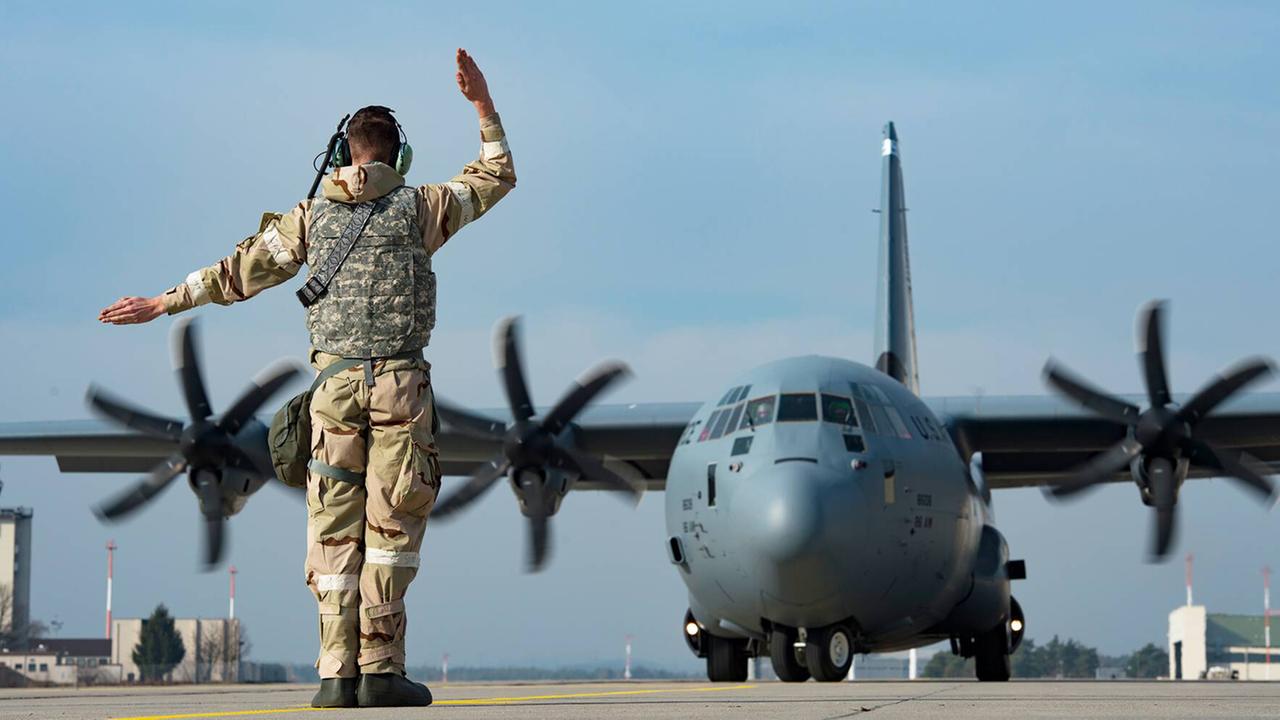 Ein Soldat steht auf dem Rollfeld der US Air Base Ramstein und gibt einem C-1301J Super Hercules Transportflugzeug Kommandos. Ein Soldat steht auf dem Rollfeld der US Air Base Ramstein und gibt einem C-1301J Super Hercules Transportflugzeug Kommandos.