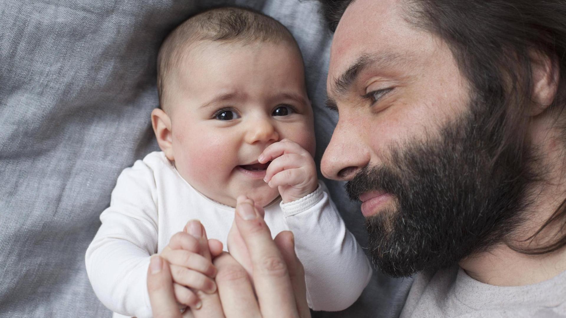 Ein Vater und sein Baby halten sich an den Händen. Ein Vater und sein Baby halten sich an den Händen.