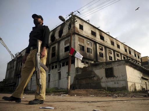 Ein pakistanischer Polizist steht vor der ausgebrannten Textilfabrik in Karachi, in der bei einem Feuer am 14. September 2012 fast 290 Menschen ums Leben kamen.