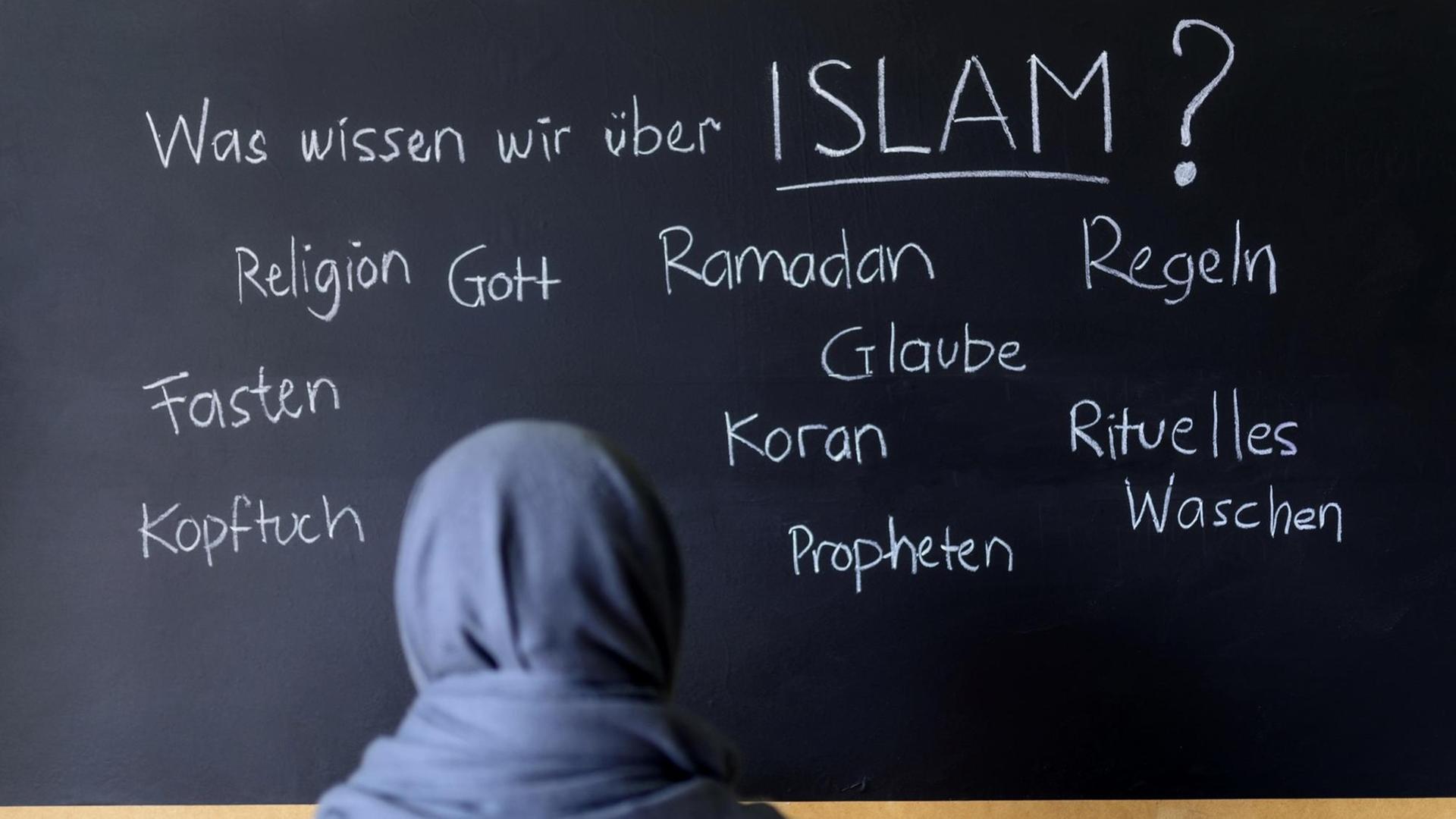 Eine muslimische Schülerin vor einer Tafel mit Begriffen aus dem Islam im Islamunterricht. (Symbolbild) Eine muslimische Schülerin vor einer Tafel mit Begriffen aus dem Islam im Islamunterricht. (Symbolbild)