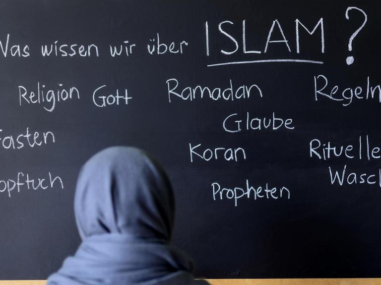 Eine muslimische Schülerin vor einer Tafel mit Begriffen aus dem Islam im Islamunterricht. (Symbolbild)